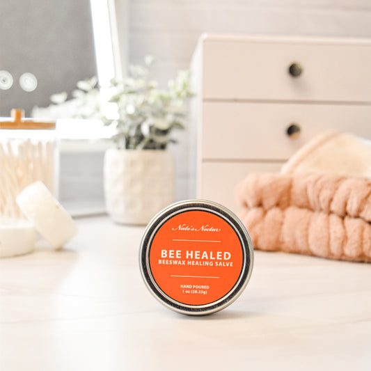 Bee Healed beeswax healing salve tin on a white surface with a blurred background