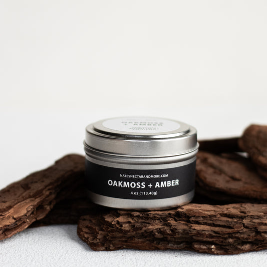 Candle jar labeled 'Oakmoss + Amber' on a white background