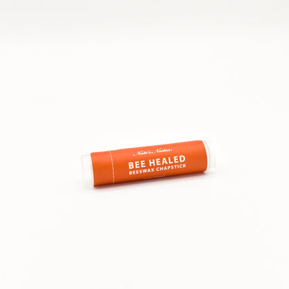 Orange lip balm stick with white text on a white background