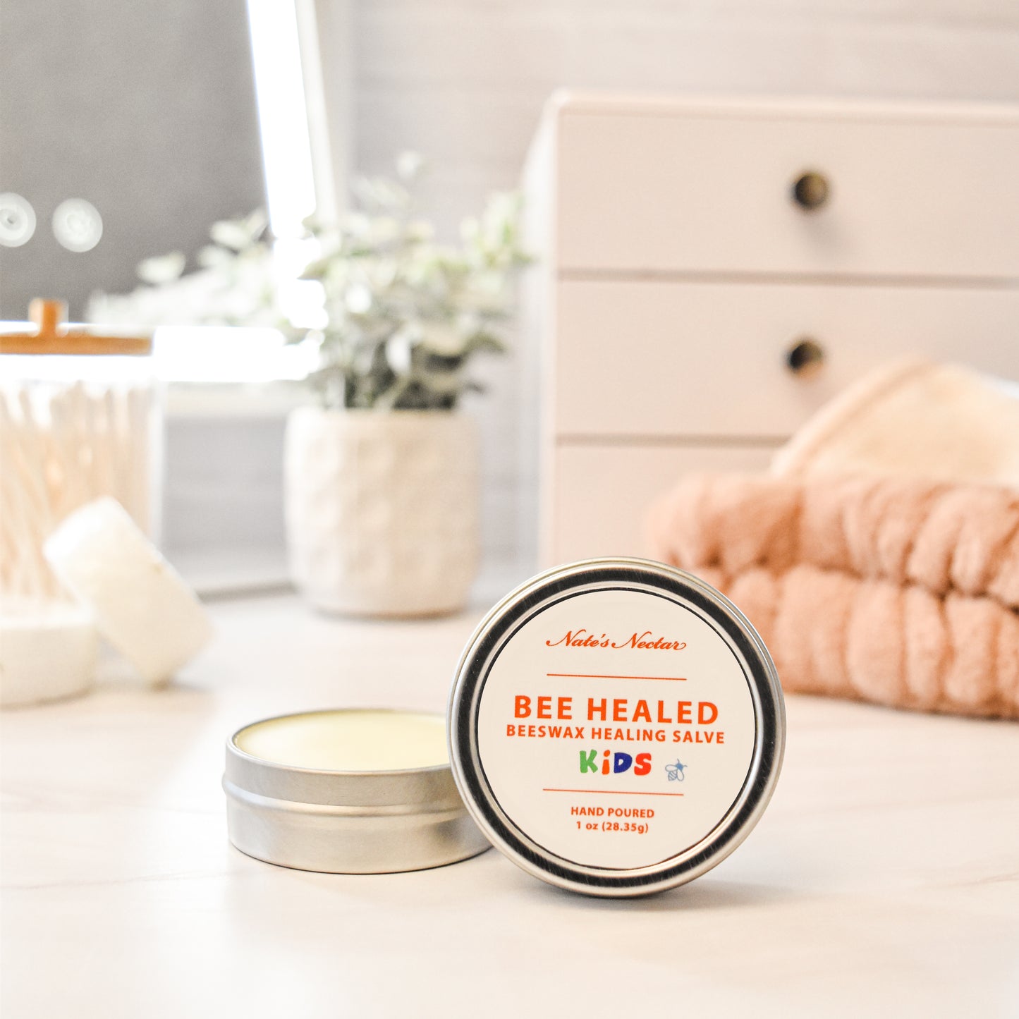 Bee Healed Kids beeswax healing salve tin on a table with a blurred background