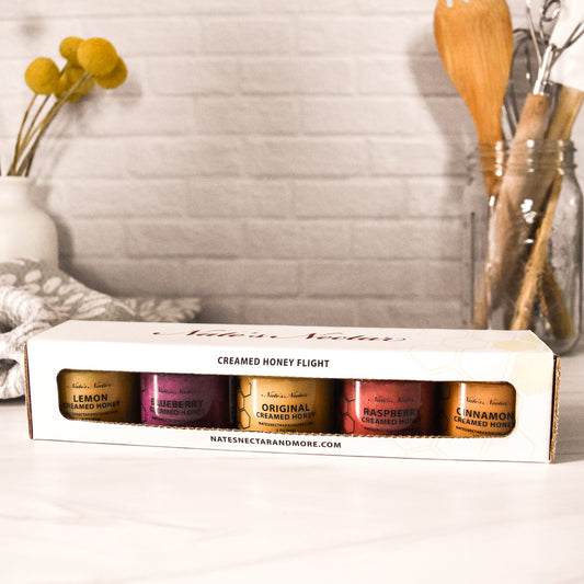 Box of creamed honey flight with various flavors on a kitchen counter.