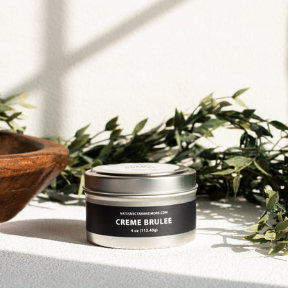 Tin of 'Creme Brèleé' on a light surface with greenery in the background