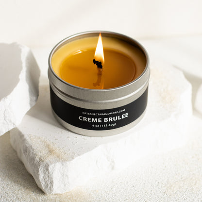 Candle in a tin labeled 'Creme Brèlee' on a light background