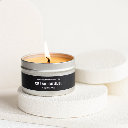 Candle labeled 'Creme Brulee' in a metallic container on a white background