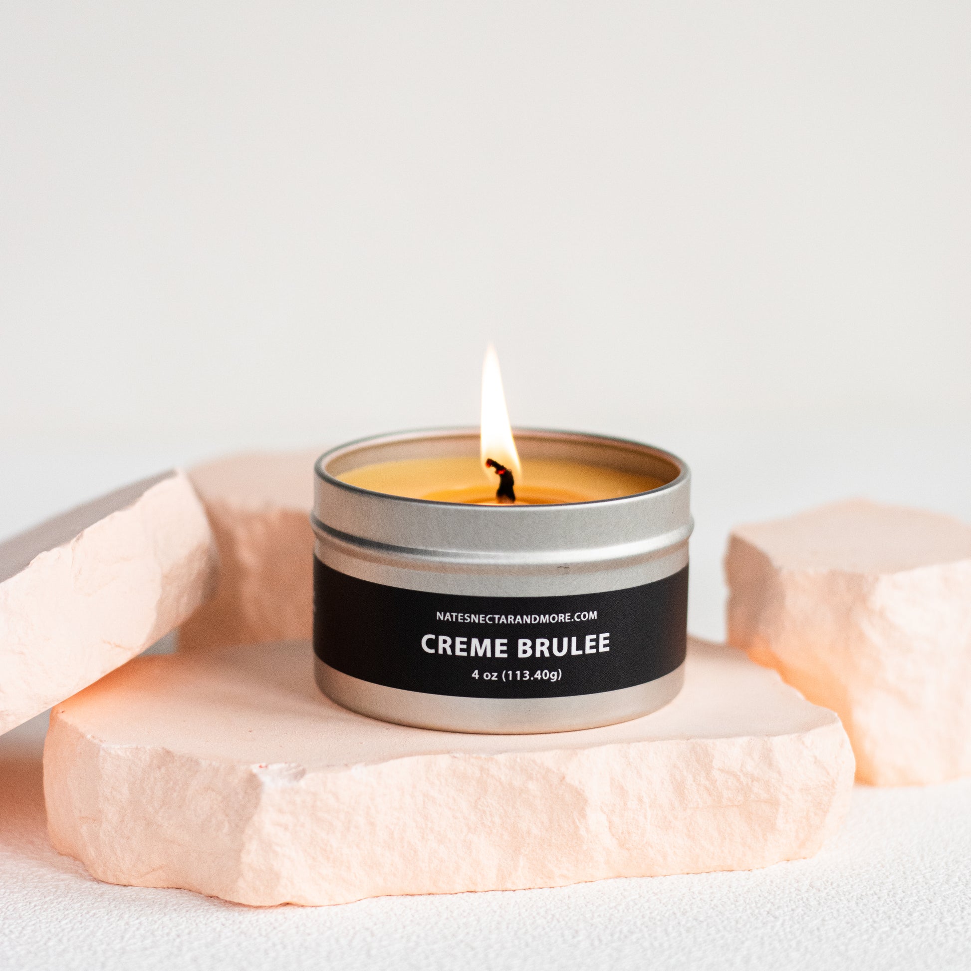 Candle in a tin labeled 'Creme Brèleé' on a light background