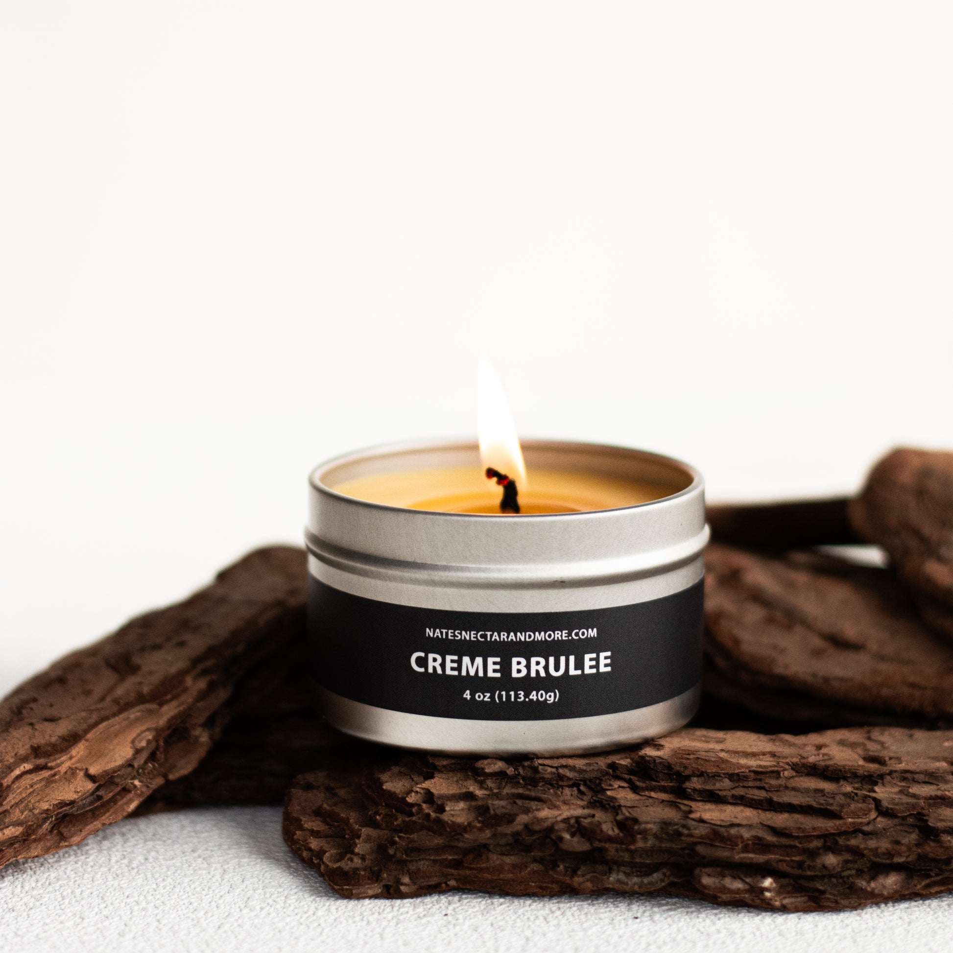 Candle in a tin labeled 'Creme Brulee' with a white background