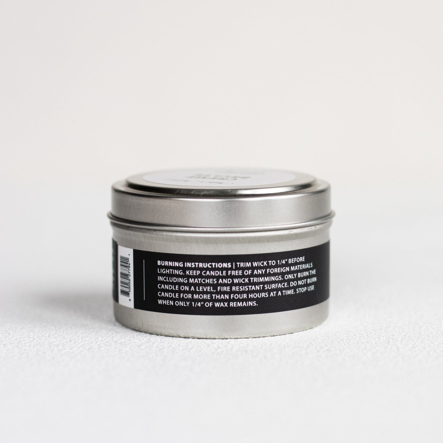 Silver candle tin with a black label on a white background