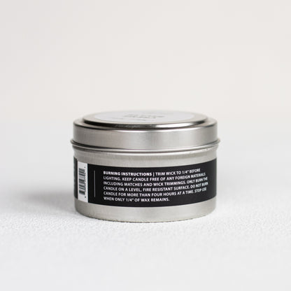 Silver candle tin with a black label on a white background