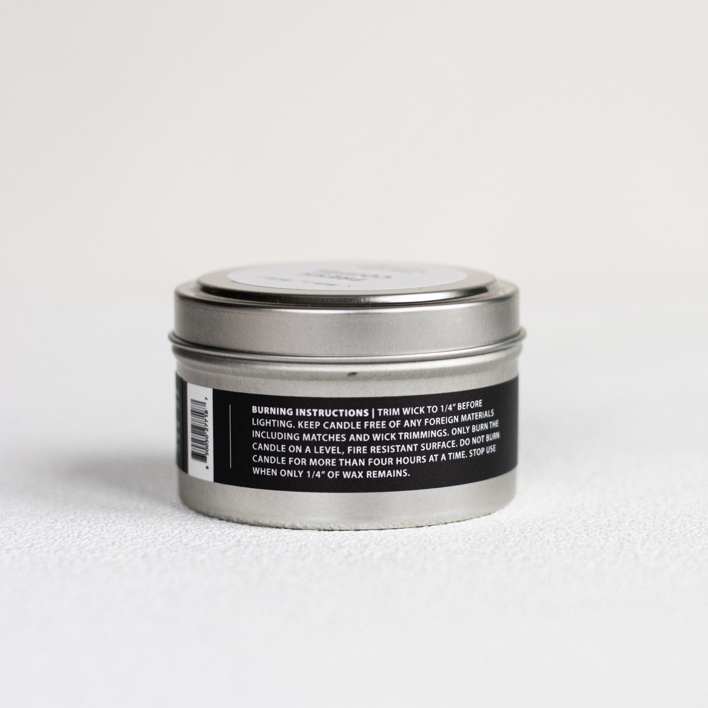 Silver candle tin with a black label on a white background