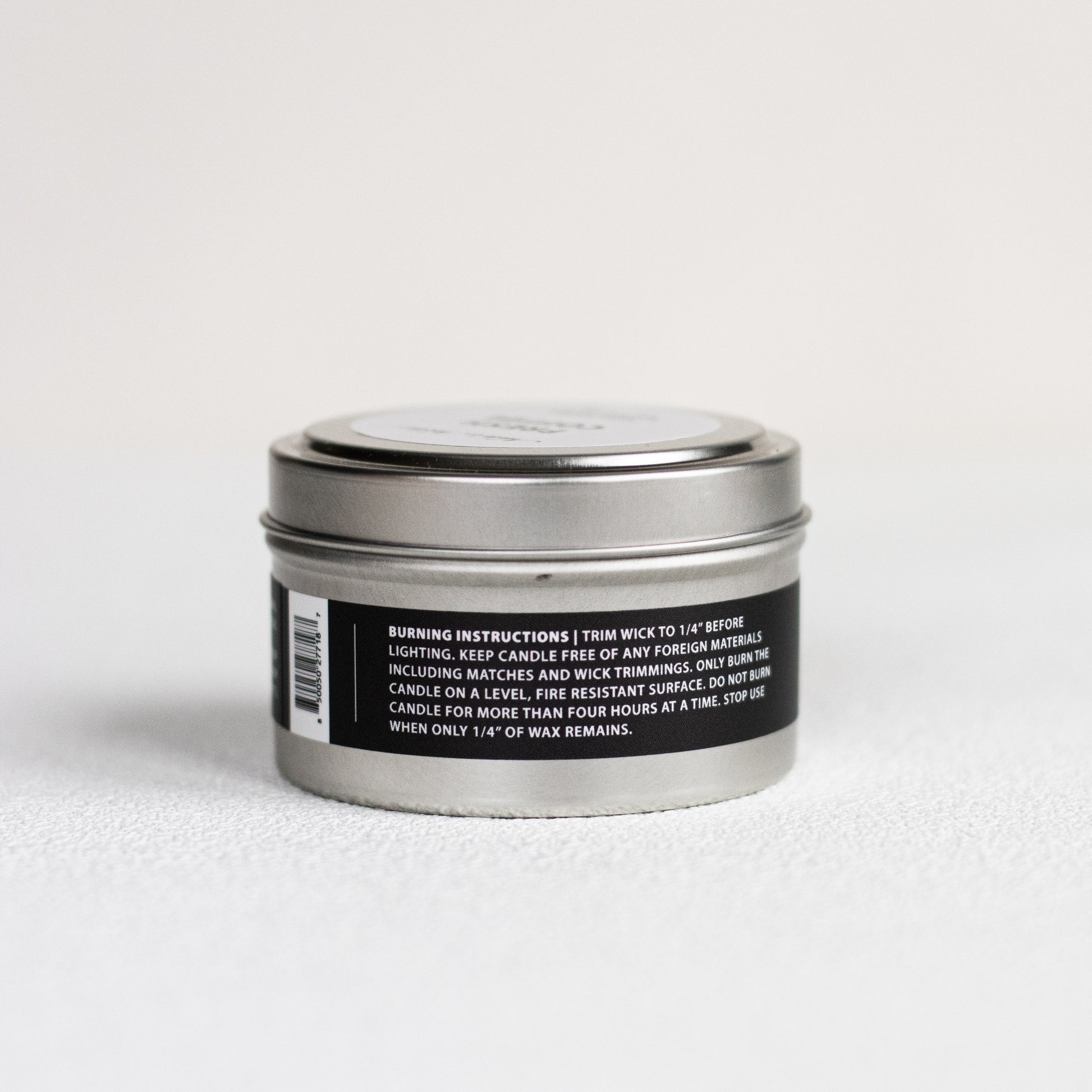 Silver candle tin with a black label on a white background
