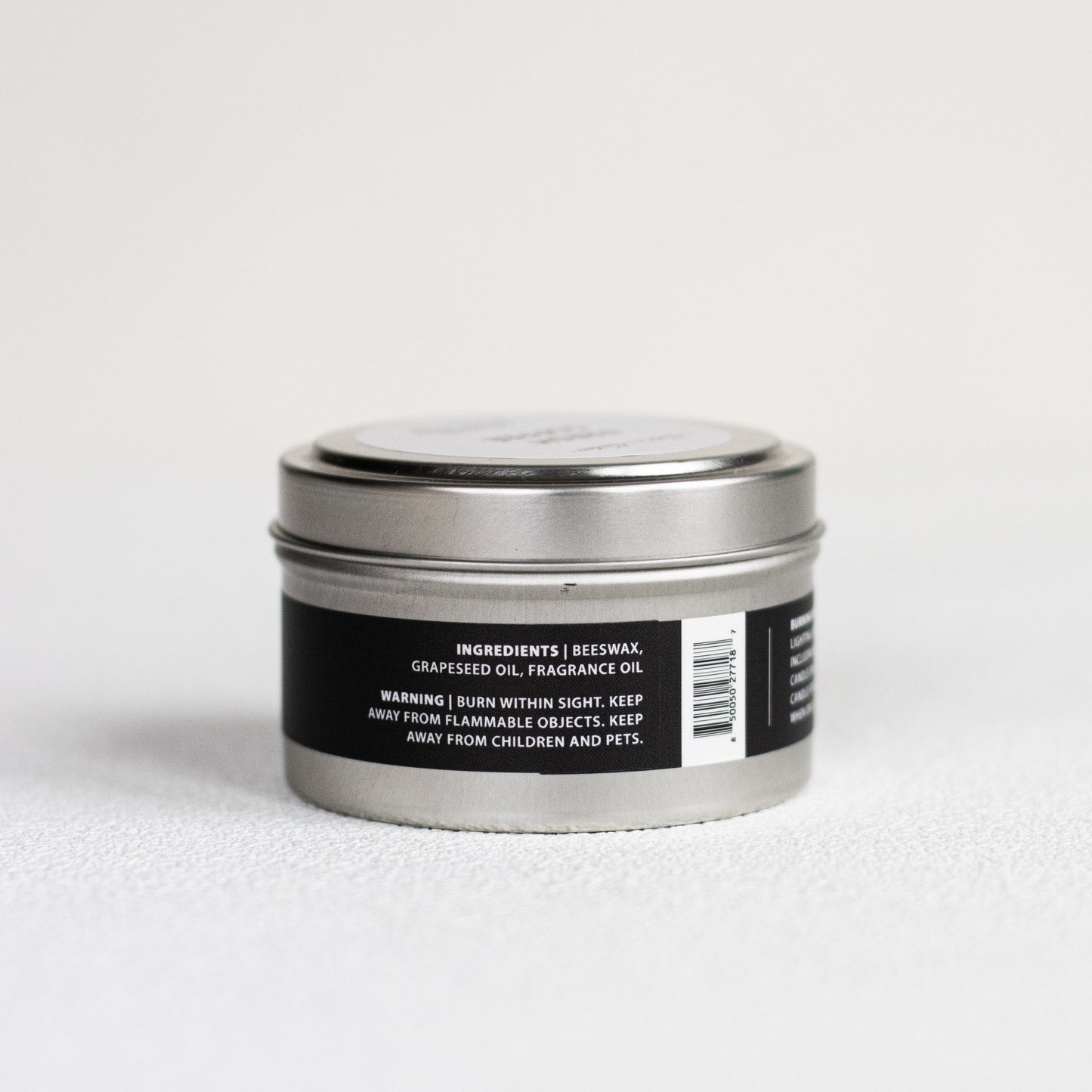Silver candle tin with black label on a white background