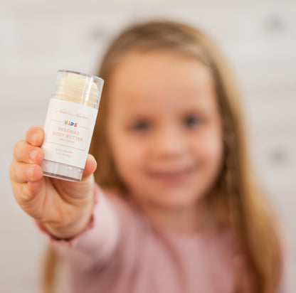 Child holding a skincare product with a blurred background
