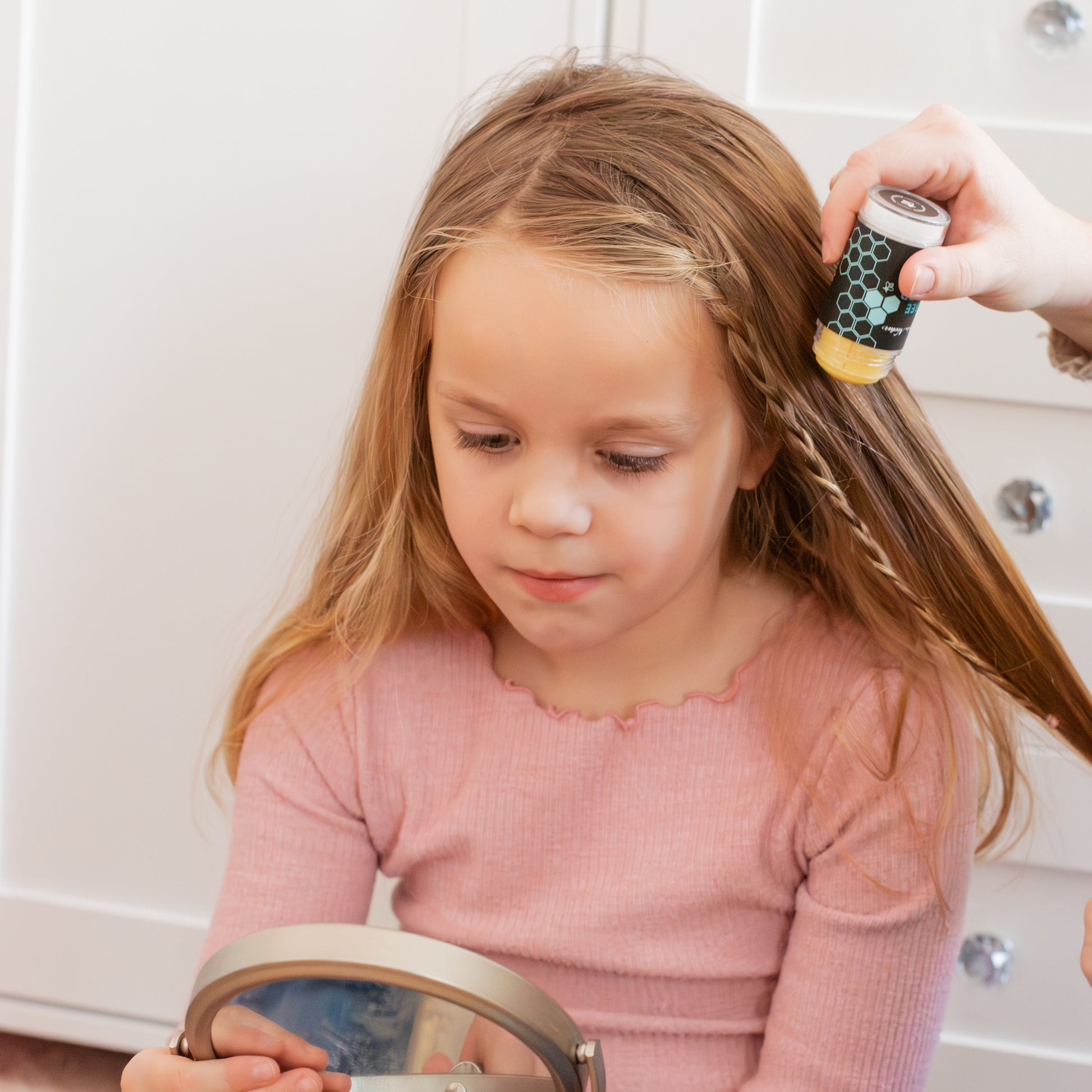 Child getting hair styled with a hair product in a bathroom setting