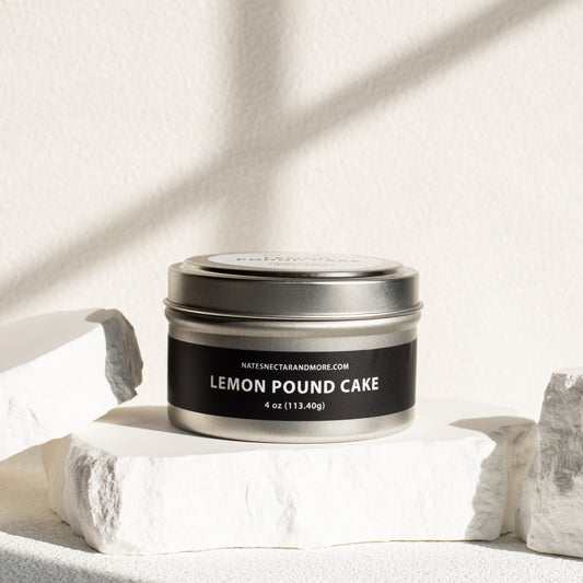 Candle tin labeled 'Lemon Pound Cake' on a light fabric background
