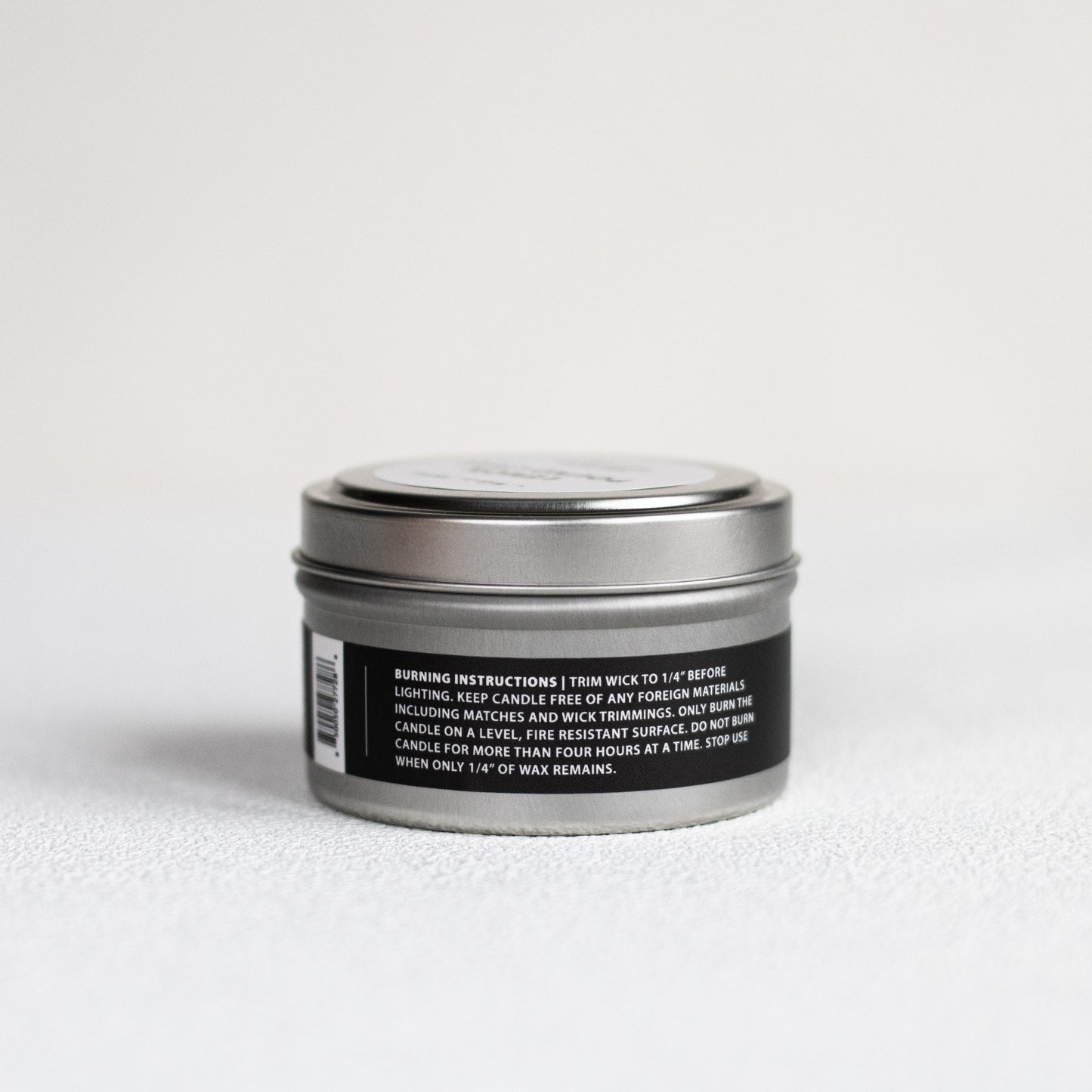 Silver candle tin with black label on a white background