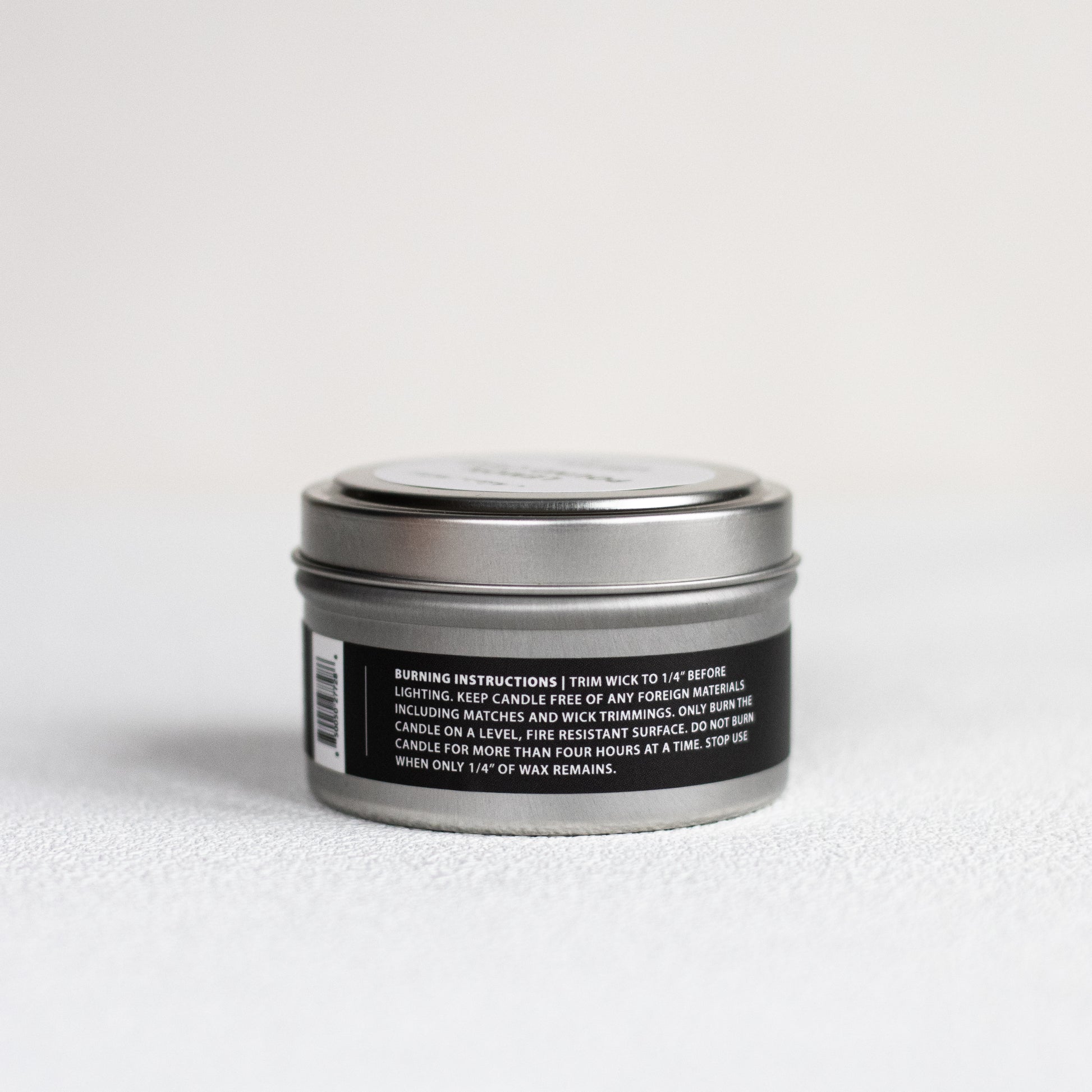 Silver candle tin with black label on a white background