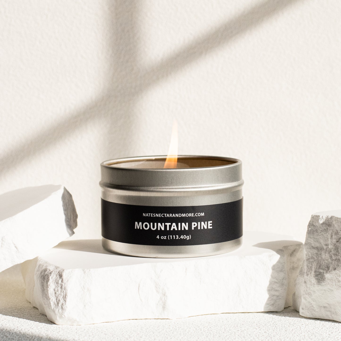 Candle in a metal tin labeled 'Mountain Pine' on a light background