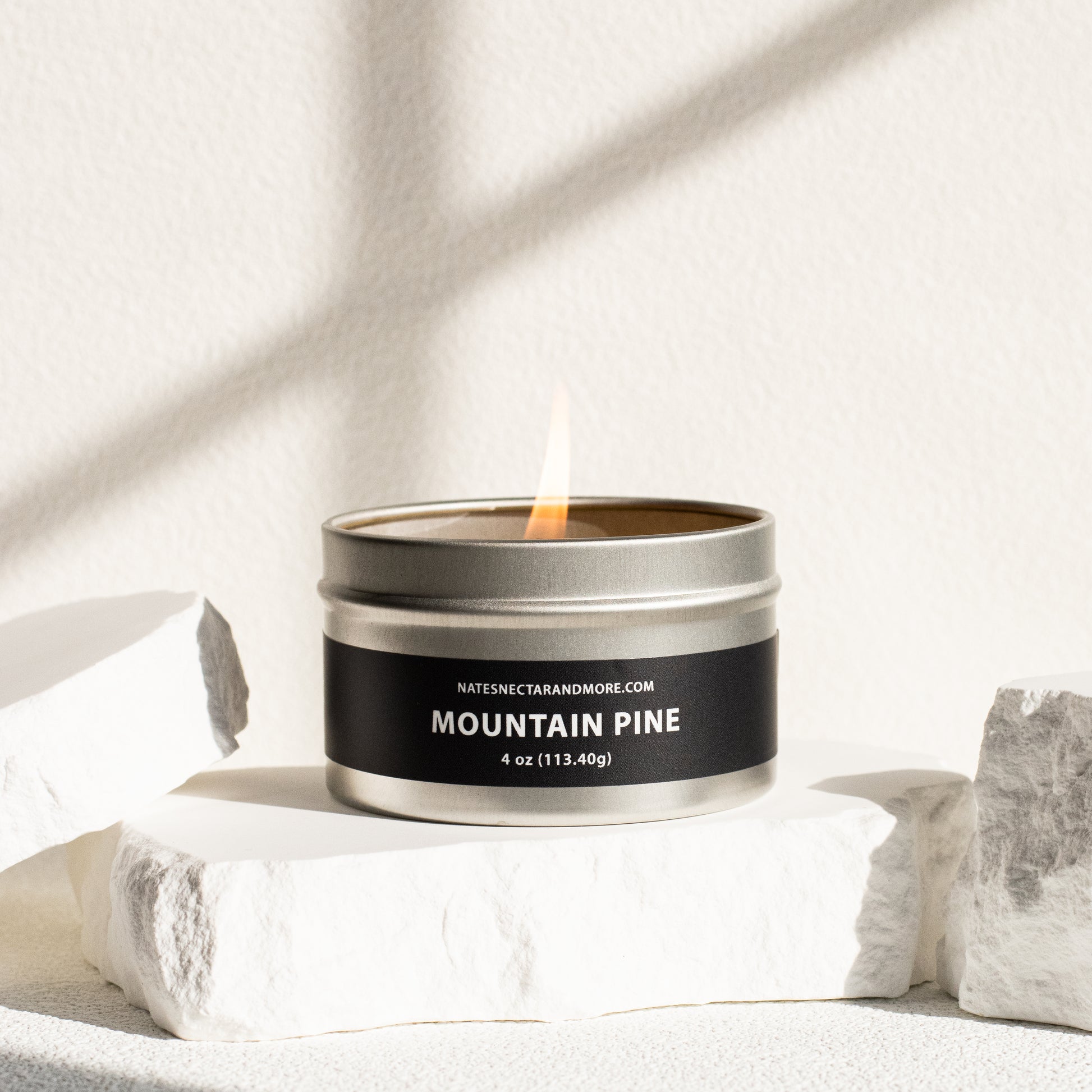 Candle in a metal tin labeled 'Mountain Pine' on a light background