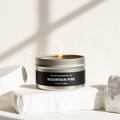Candle in a metal tin labeled 'Mountain Pine' on a light background