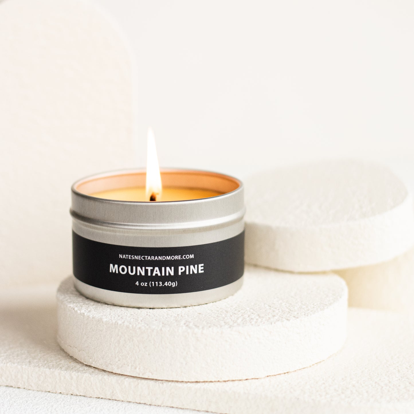 Candle in a metal tin labeled 'Mountain Pine' on a light background