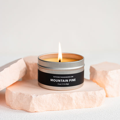 Candle in a tin labeled 'Mountain Pine' on a light background