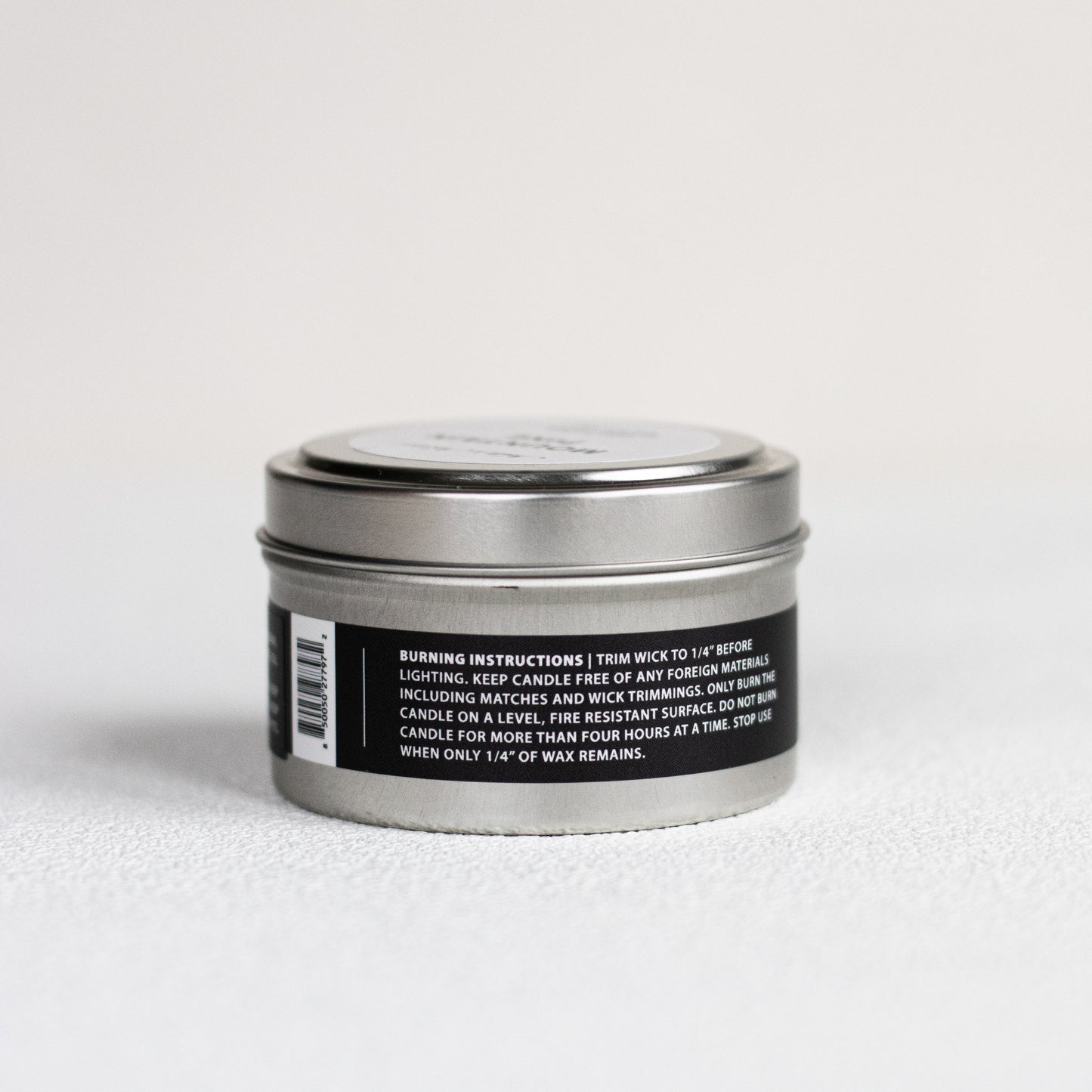 Silver candle tin with black label on a white background