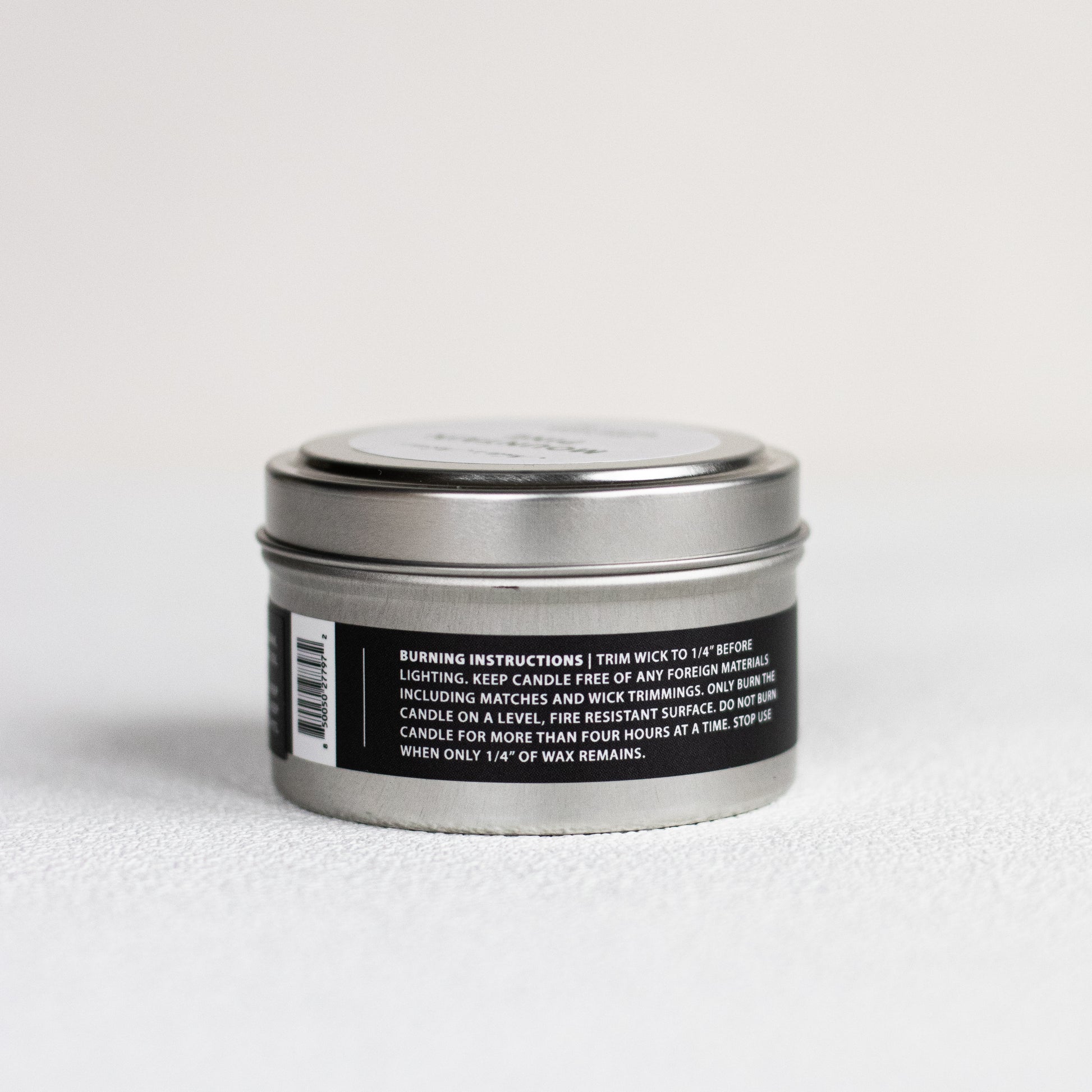 Silver candle tin with black label on a white background