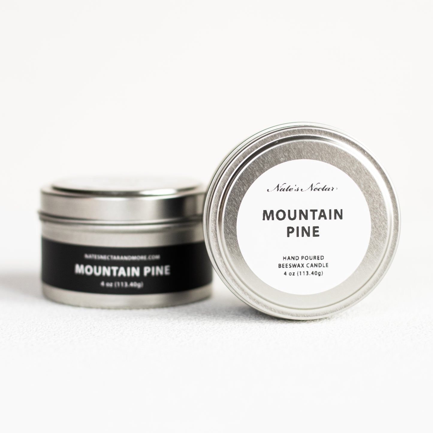 Two tins of 'Mountain Pine' candle with labels on a white background