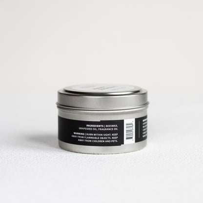 Silver candle tin with black label on a light gray background
