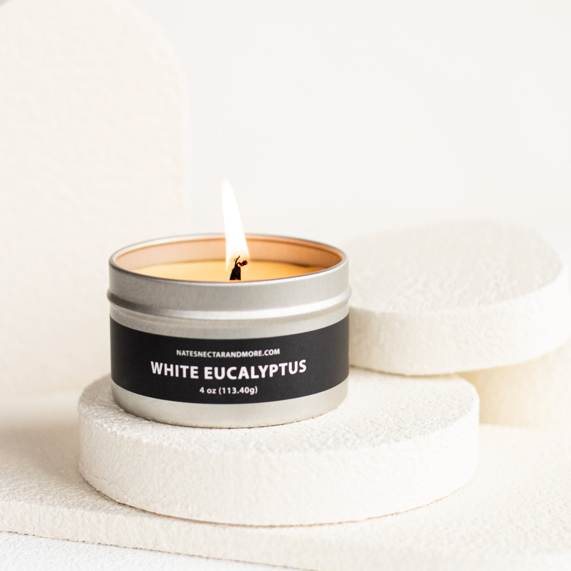 Candle in a metal tin labeled 'White Eucalyptus' on a light background