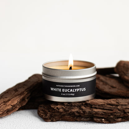 Candle in a metal tin labeled 'White Eucalyptus' on a white background with wooden elements.