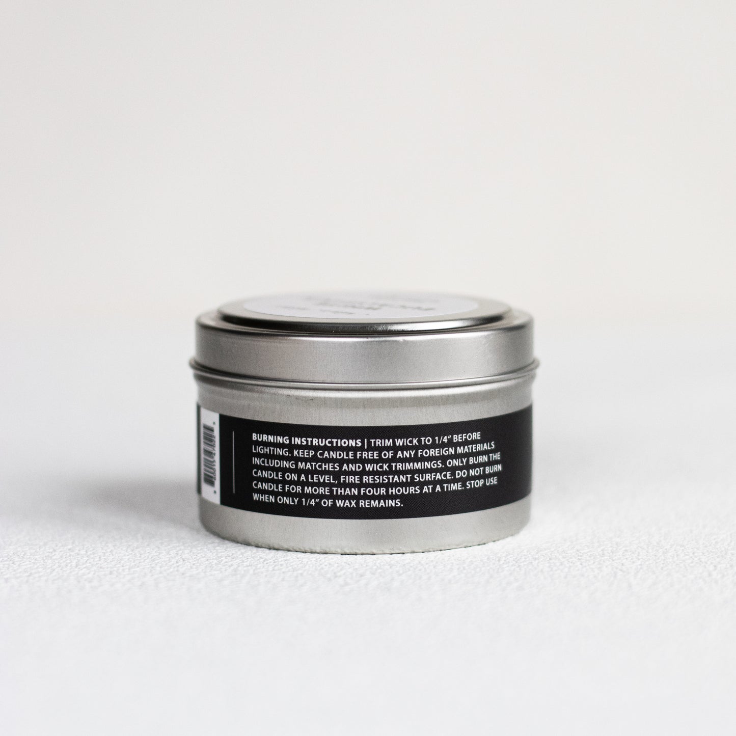 Silver candle tin with black label on a white background