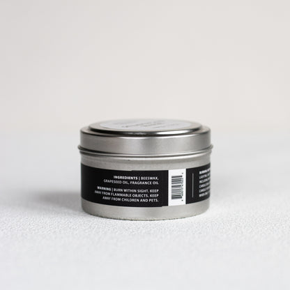 Silver candle tin with black label on a light gray background